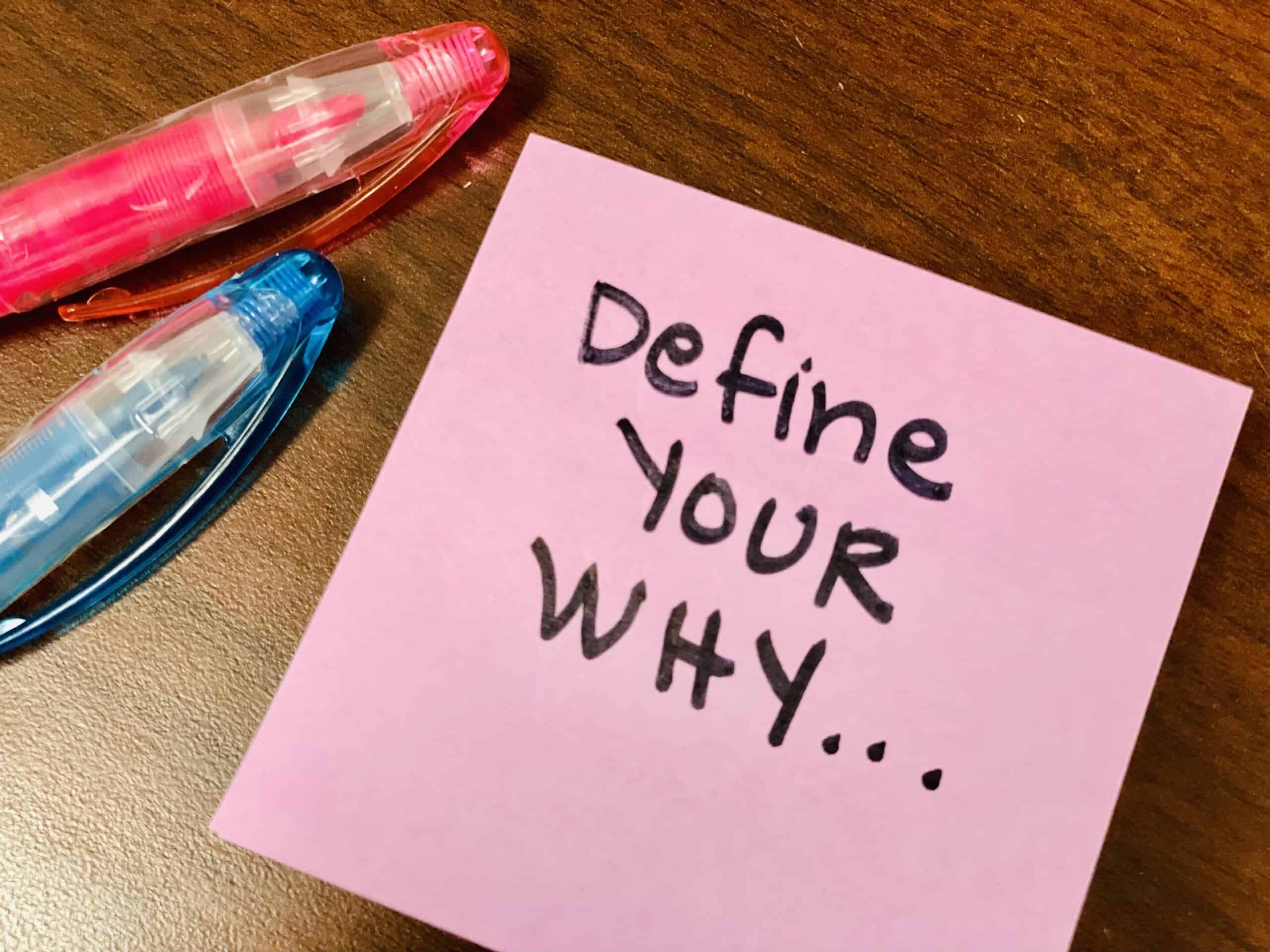 Two pens and a pink post it note that reads 
